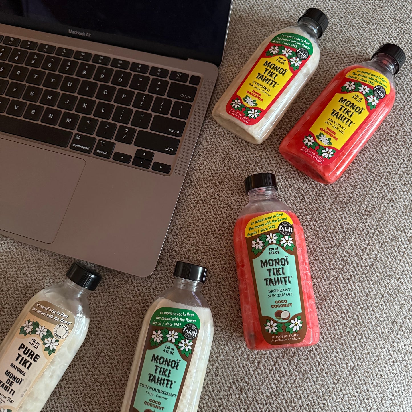 Bottles of Monoi Tiki Tahiti products on a wooden surface