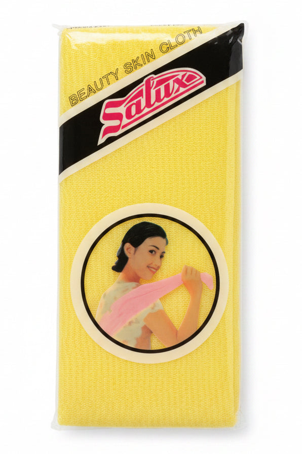 A yellow Salux beauty skin cloth in its original plastic packaging, placed on a light brown wooden surface.