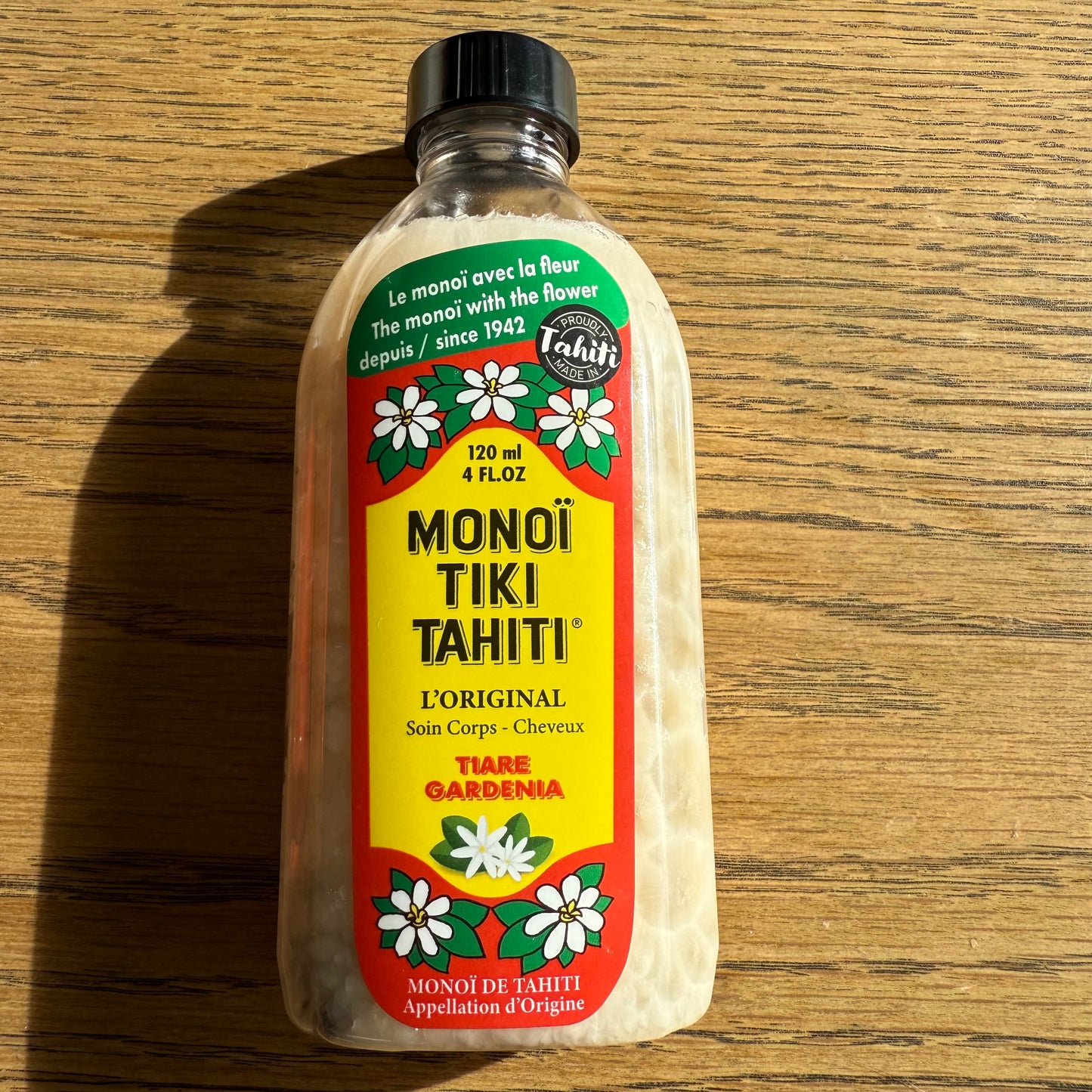 Bottles of Monoi Tiki Tahiti products on a wooden surface