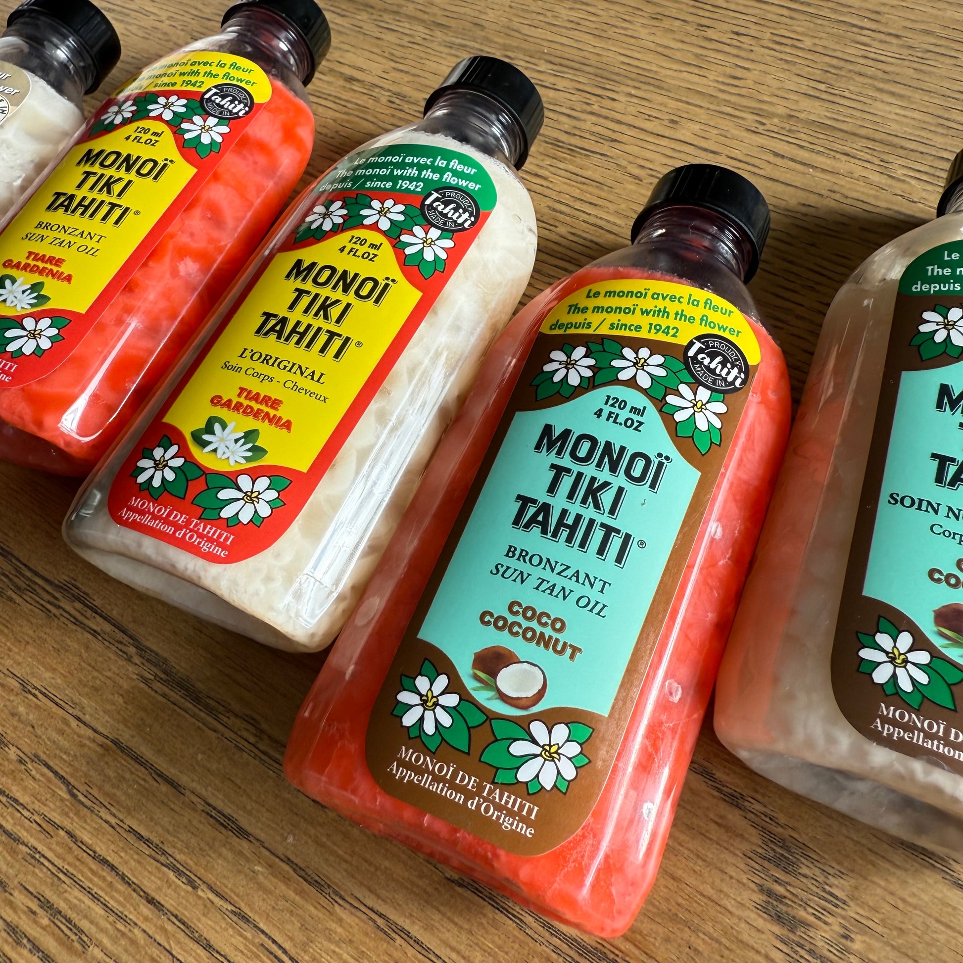 Bottles of Monoi Tiki Tahiti products on a wooden surface