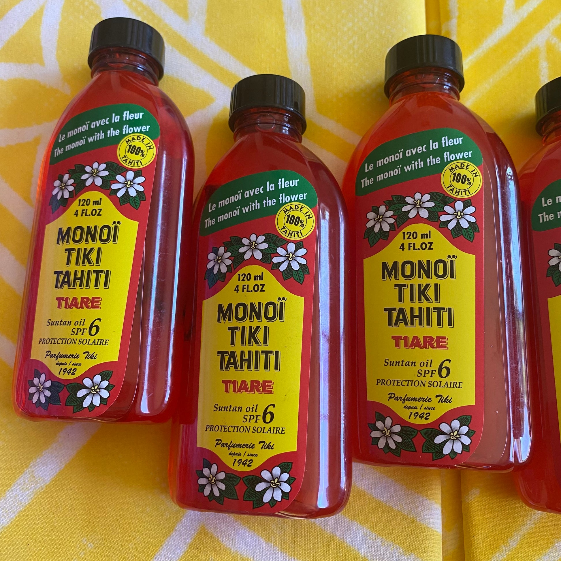 Bottles of Monoi Tiki Tahiti products on a wooden surface