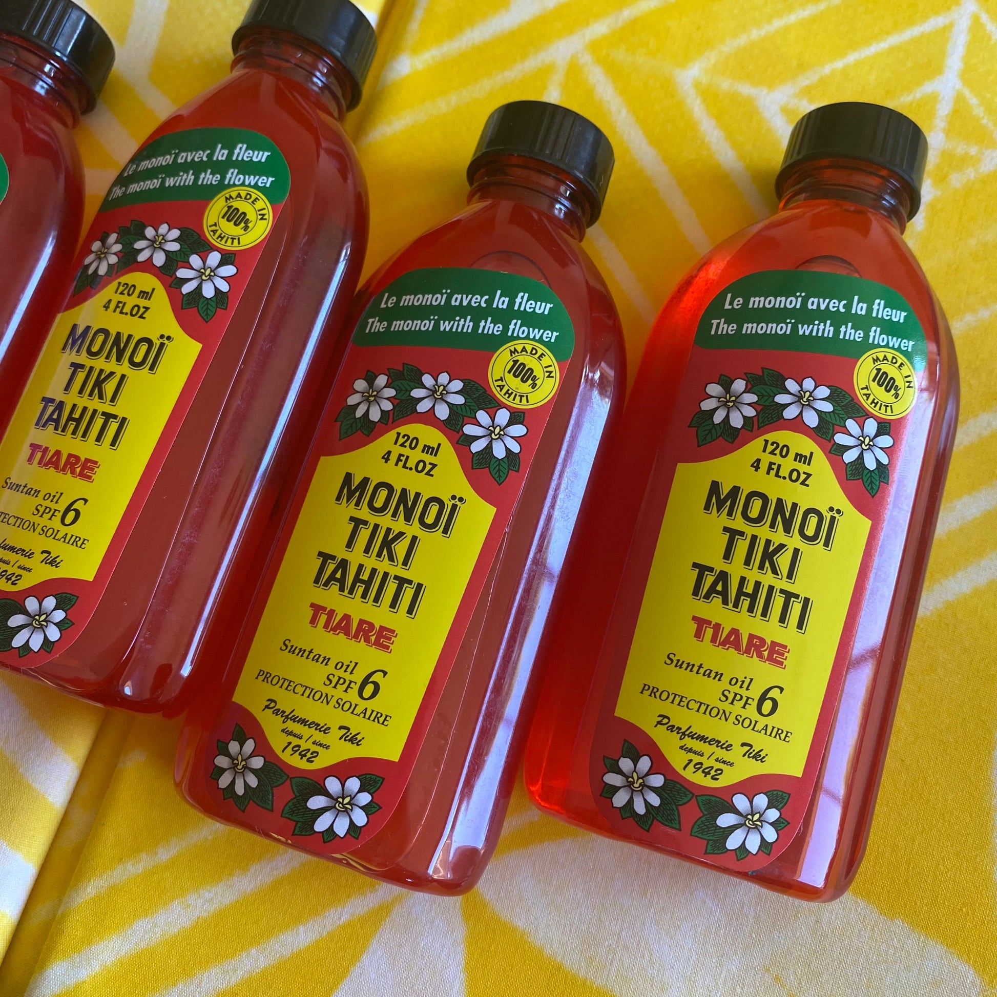 Bottles of Monoi Tiki Tahiti products on a wooden surface