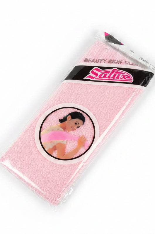 A pink Salux Beauty Skin Glow hand towel, still in its plastic packaging, placed on a light wooden tabletop.
