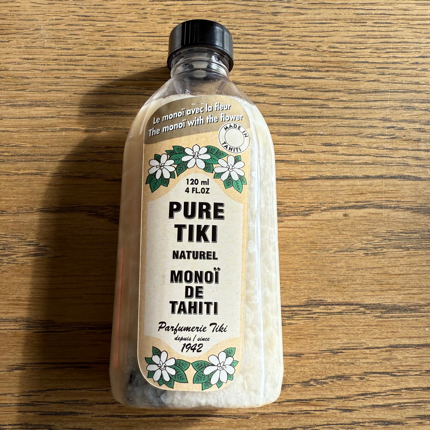 Bottles of Monoi Tiki Tahiti products on a wooden surface