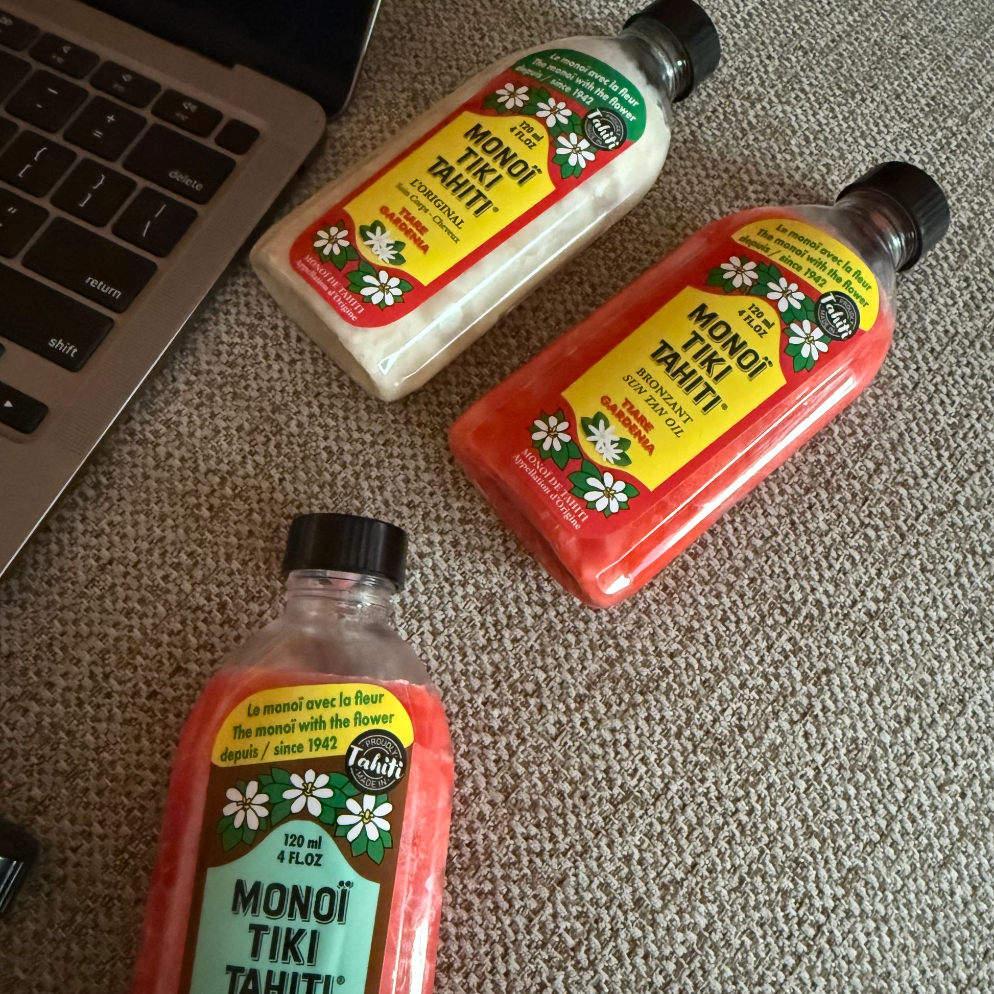 Bottles of Monoi Tiki Tahiti products on a wooden surface