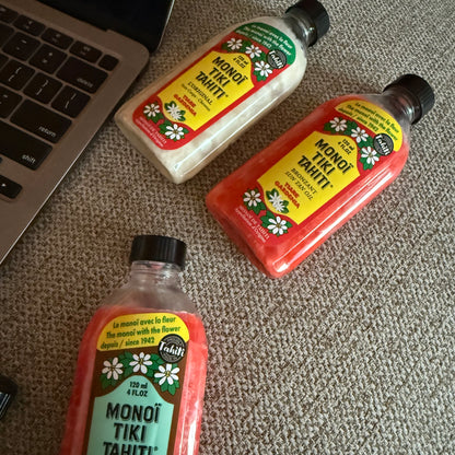 Bottles of Monoi Tiki Tahiti products on a wooden surface