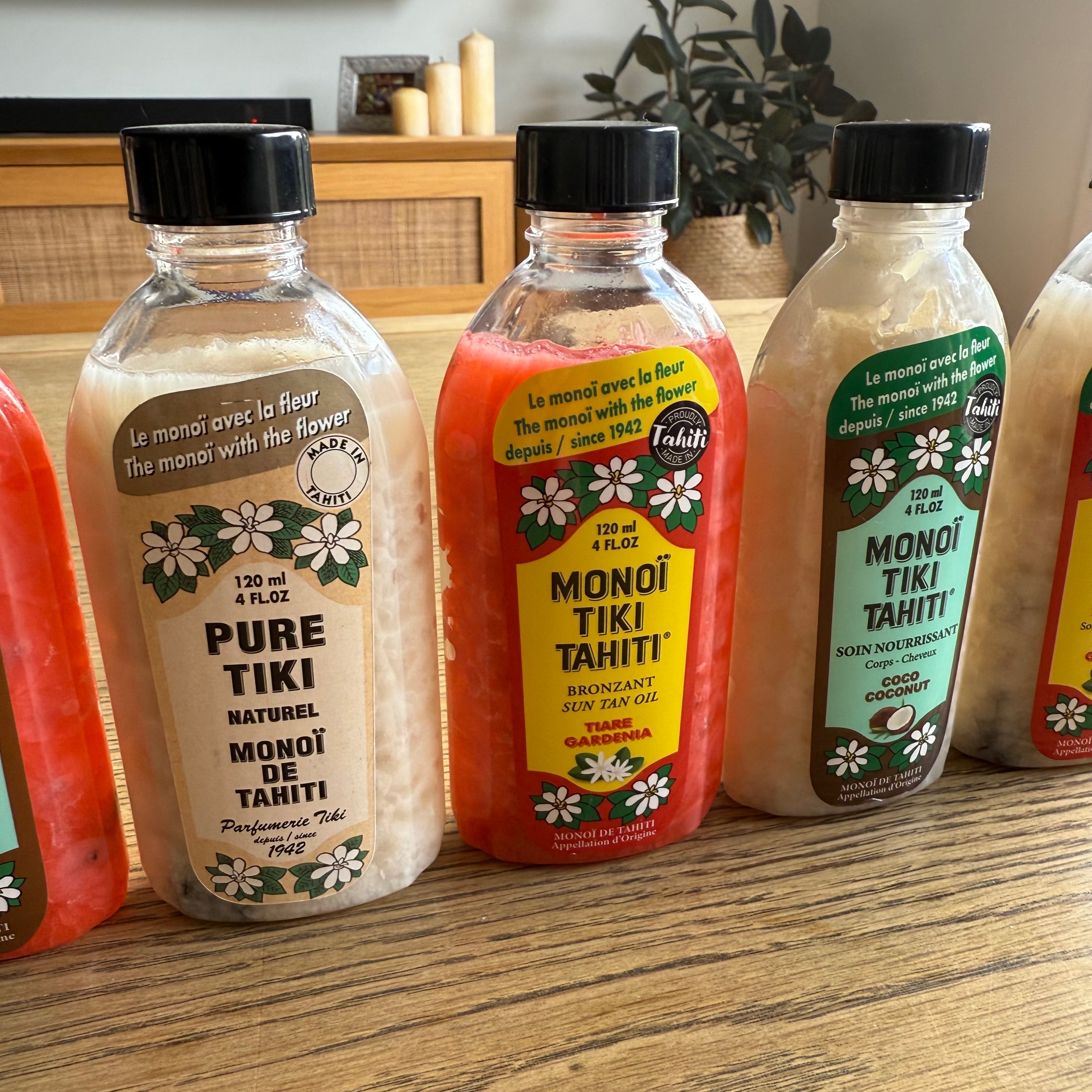 Bottles of Monoi Tiki Tahiti products on a wooden surface