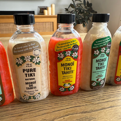 Bottles of Monoi Tiki Tahiti products on a wooden surface