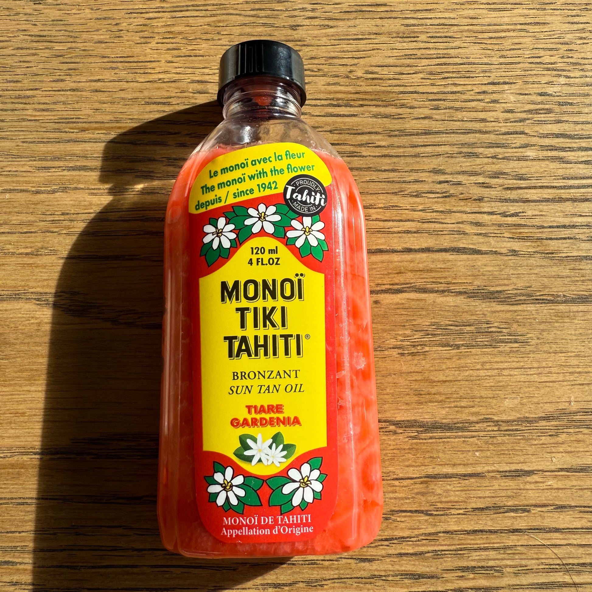 Bottles of Monoi Tiki Tahiti products on a wooden surface