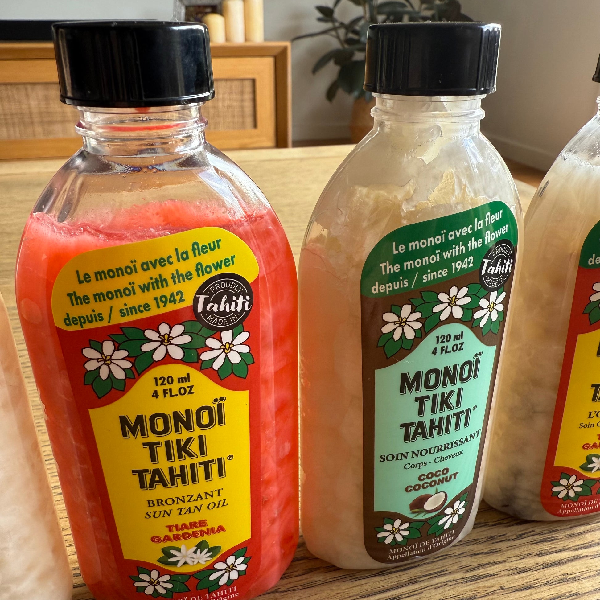 Bottles of Monoi Tiki Tahiti products on a wooden surface