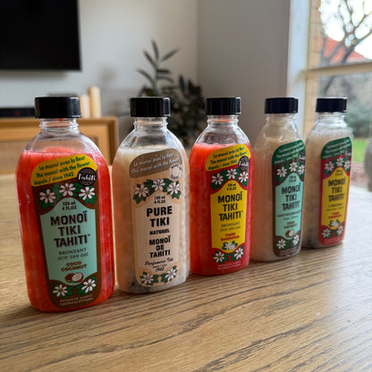 Bottles of Monoi Tiki Tahiti products on a wooden surface