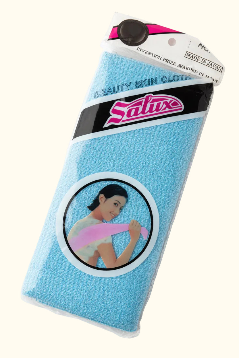 A packaged blue Satuse Beauty Skin Glove on a wooden tabletop. The product is in its original plastic packaging with a cardboard header and a circular graphic label showing a woman holding the glove.