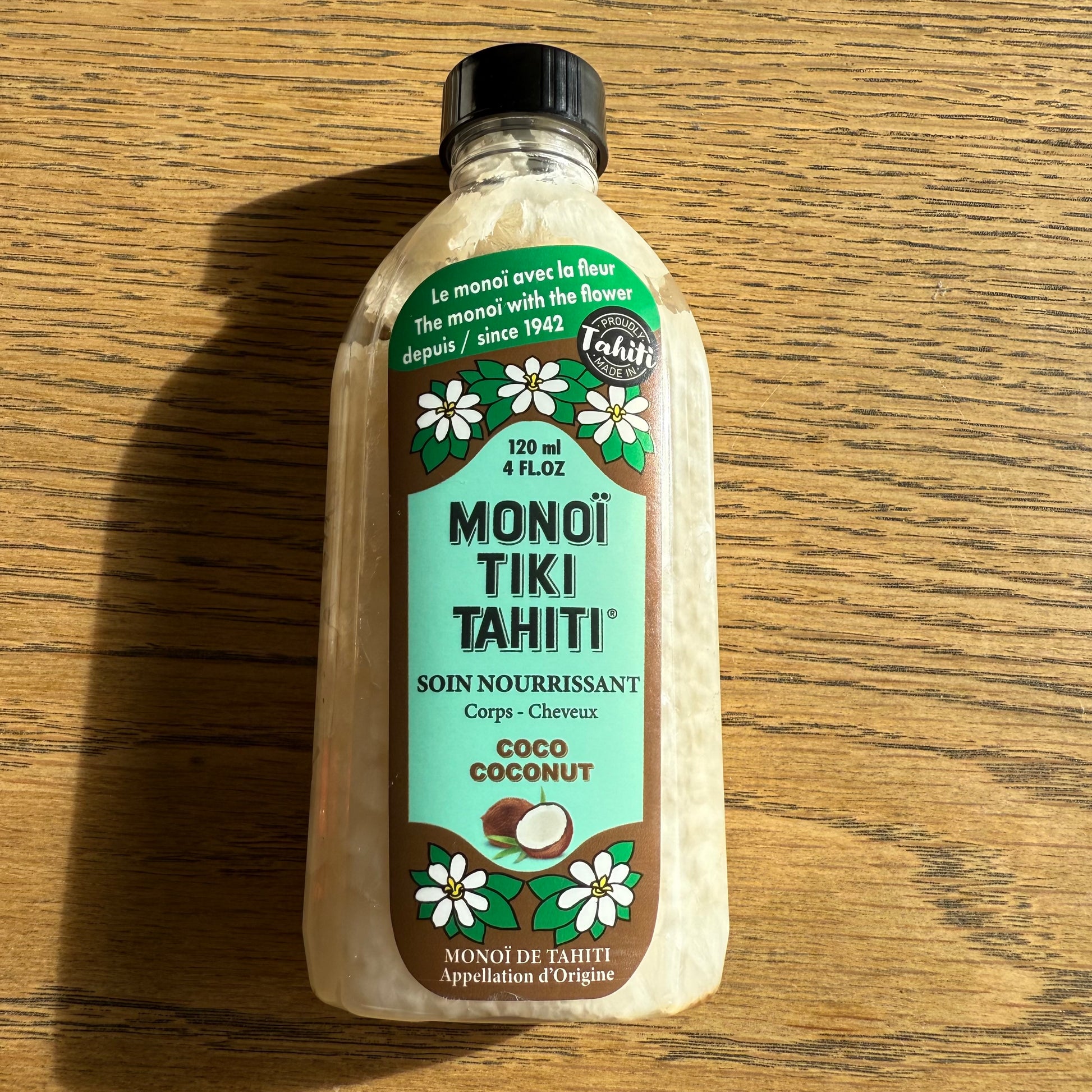 Bottles of Monoi Tiki Tahiti products on a wooden surface