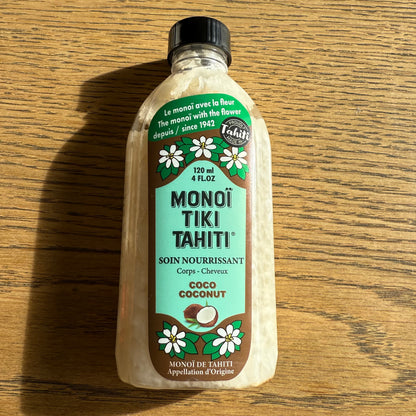 Bottles of Monoi Tiki Tahiti products on a wooden surface