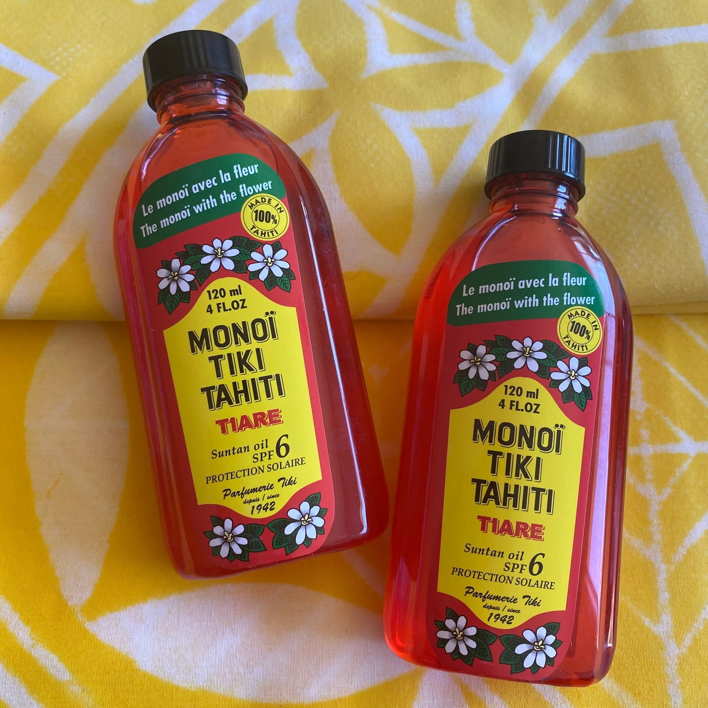 Bottles of Monoi Tiki Tahiti products on a wooden surface