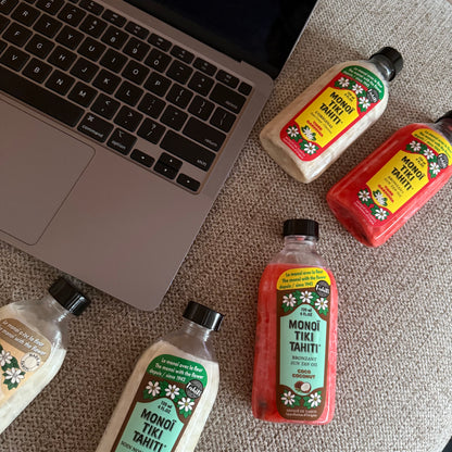 Bottles of Monoi Tiki Tahiti products on a wooden surface