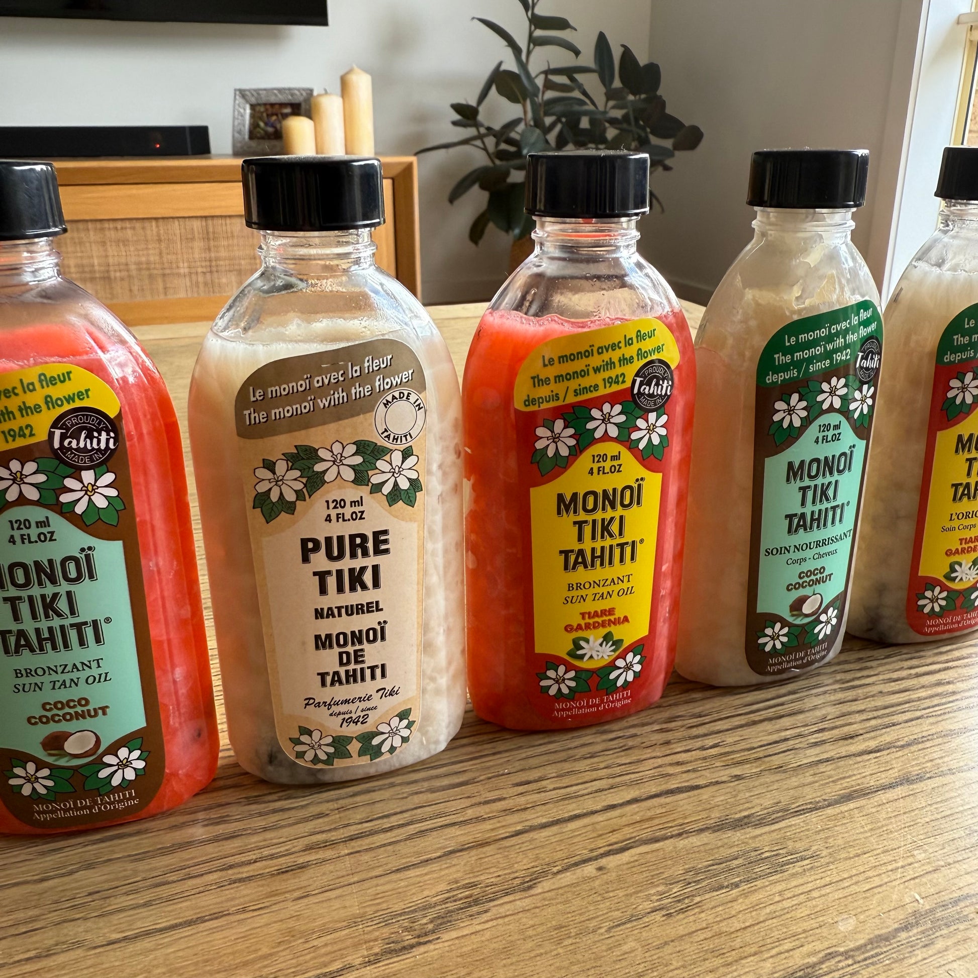 Bottles of Monoi Tiki Tahiti products on a wooden surface