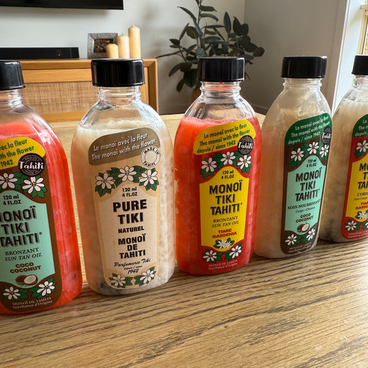 Bottles of Monoi Tiki Tahiti products on a wooden surface