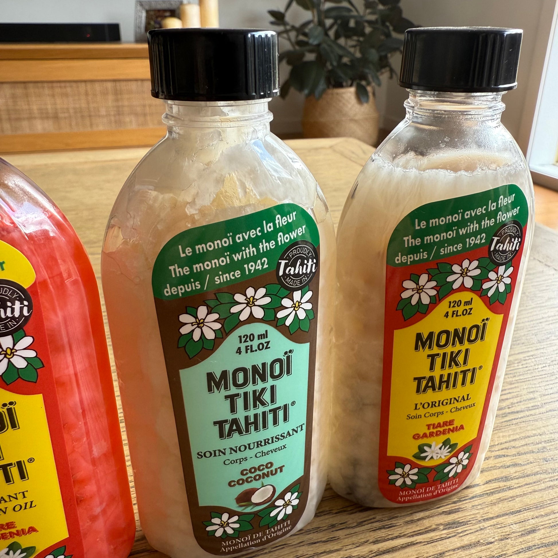Bottles of Monoi Tiki Tahiti products on a wooden surface