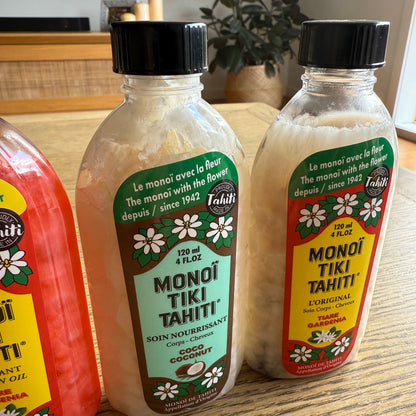 Bottles of Monoi Tiki Tahiti products on a wooden surface
